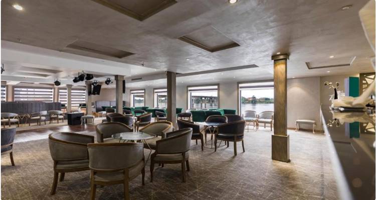 Un spacieux salon moderne avec des sièges confortables et une vue sur le fleuve à travers de grandes fenêtres.