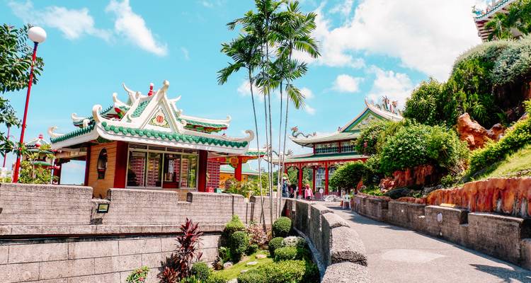 Des pavillons de temple taoïste aux couleurs éclatantes s'élèvent le long d'un sentier sinueux au milieu d'une verdure entretenue et de ciels bleus.