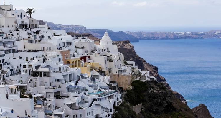 Les bâtiments emblématiques blanchis à la chaux de Santorin en cascade vers la mer Égée d'un bleu azur.