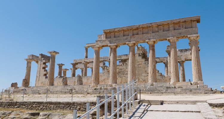 Les ruines bien préservées d'un temple grec antique aux colonnes doriques s'élèvent sous un ciel d'un bleu éclatant.