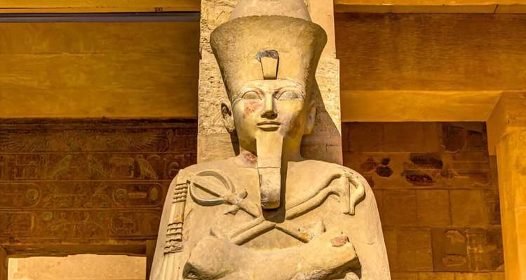 Close-up of an ancient Egyptian pharaoh statue lit by warm interior lighting.