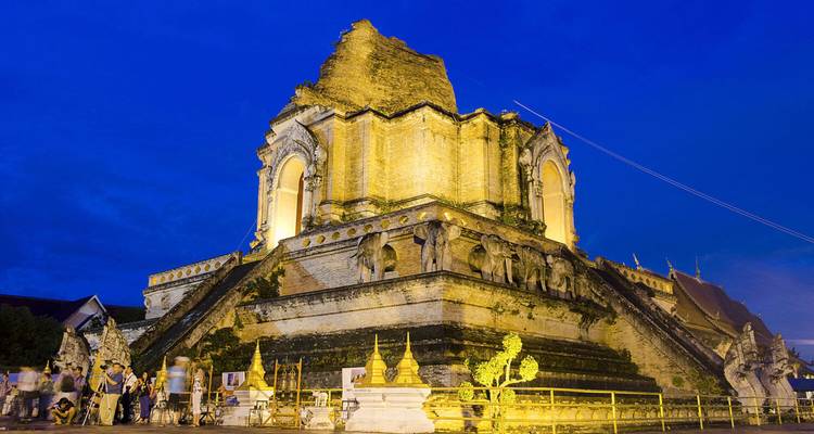 Erleuchtete antike Stupa des Wat Chedi Luang, die gegen einen tiefblauen Abendhimmel leuchtet