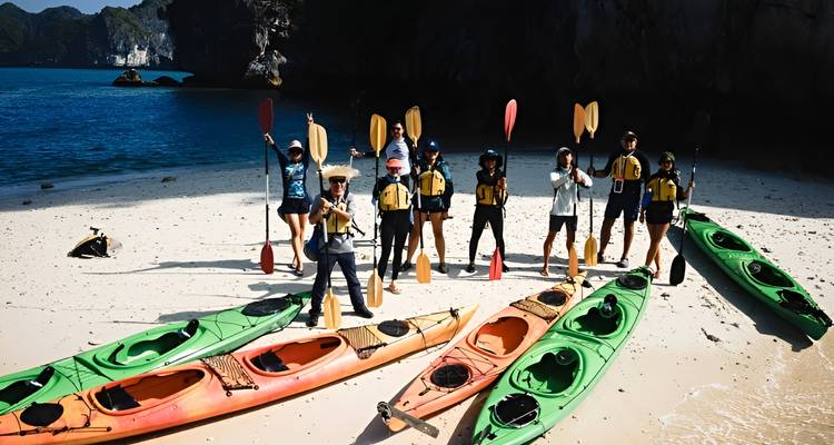 Grupo entusiasta posando con kayaks coloridos en una playa de arena blanca junto a un mar turquesa
