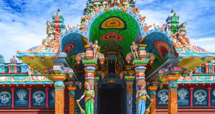 Exuberantly colorful Hindu temple façade rich with statues and decorative columns.