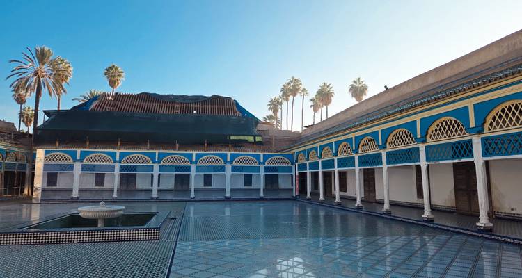 Cour palatiale spacieuse avec carrelage réfléchissant, fontaine et section en rénovation avec échafaudage.