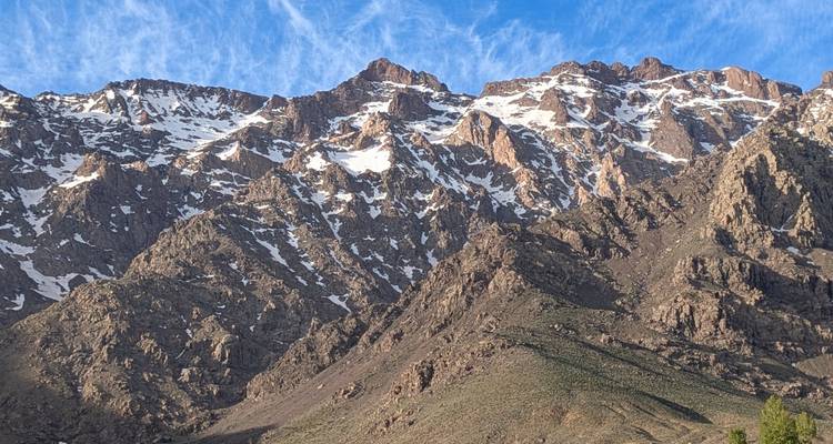 Les pics rocheux de l'Atlas avec la neige printanière persistante sous un ciel matinal bleu et limpide.