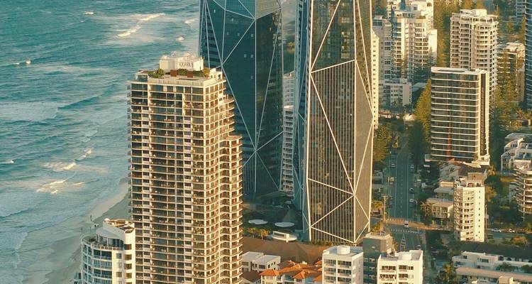 Golden light on modern glass skyscrapers lining the beachside avenue of Surfers Paradise.