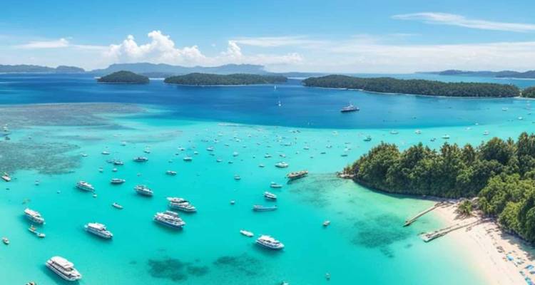 Vue aérienne d'une baie turquoise parsemée de yachts et de petites îles boisées.