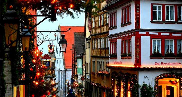 Narrow medieval street in Rothenburg ob der Tauber decorated with glowing Christmas lights, ornaments and half-timbered buildings