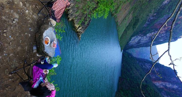 Un viajero en solitario recostado en una silla de campamento con snacks y café contemplando un tranquilo lago de cañón azul.
