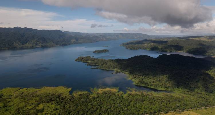 Wide aerial panorama of Lake Arenal dotted with islands and surrounded by green ridges.