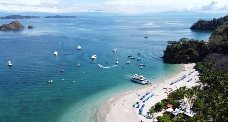 Aerial view of pristine Tortuga Island beach with anchored boats and turquoise water.