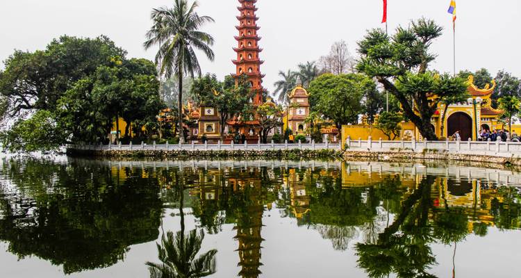 Tran Quoc Pagoda weerspiegeld in een stil meer met weelderige bomen en sierlijke poorten in Hanoi