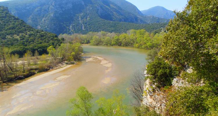 Un fleuve d'émeraude sinueux serpente entre des montagnes boisées et des bancs de sable dans le nord de la Grèce.