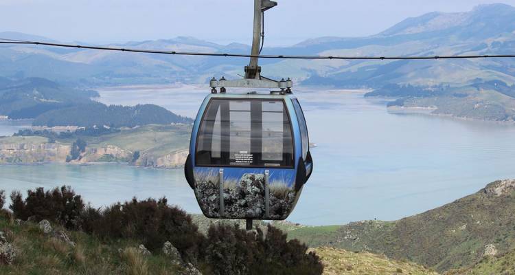 Cabina de góndola panorámica moviéndose sobre un lago y colinas verdes ondulantes en Skyline Rotorua.