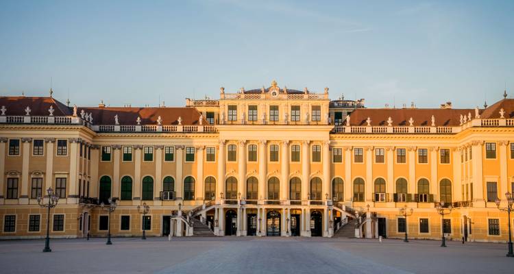 Vue symétrique de face du Palais de Schönbrunn illuminé chaleureusement dans la douce lumière du soir.