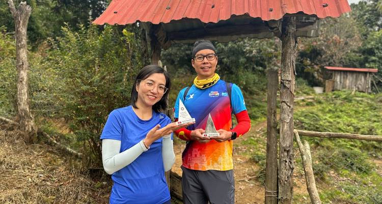 Deux coureurs tiennent fièrement de petits trophées à côté d'une porte rustique à la campagne