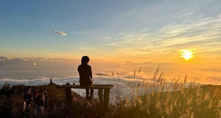Voyageur solitaire assis sur un banc admirant un coucher de soleil coloré au-dessus des nuages