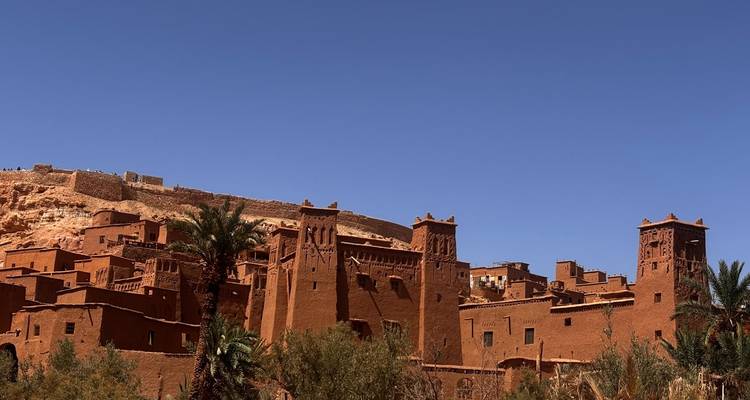 Les kasbas en briques d'argile d'Aït Benhaddou s'élèvent contre un ciel désertique d'un bleu limpide.