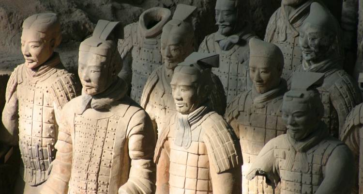 Primer plano de estatuas de Guerreros de Terracota a tamaño real iluminadas dentro de la fosa de excavación