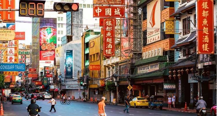 Rue animée et colorée du quartier chinois de Bangkok avec des enseignes chinoises au néon et la circulation routière.