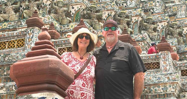 Un couple pose devant les détails en céramique complexes du temple Wat Arun de Bangkok.