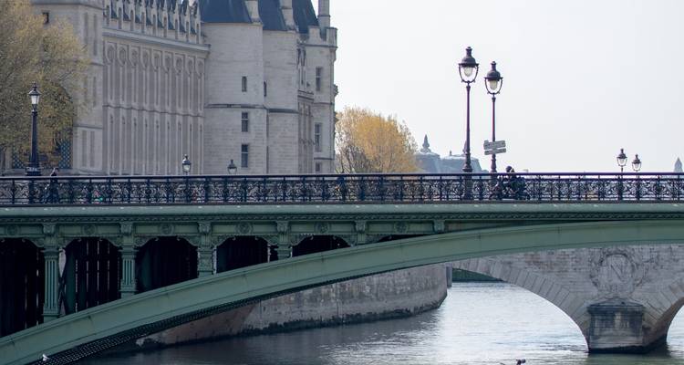 Pont historique en pierre enjambant la Seine avec des réverbères et des bâtiments riverains à la lumière douce.
