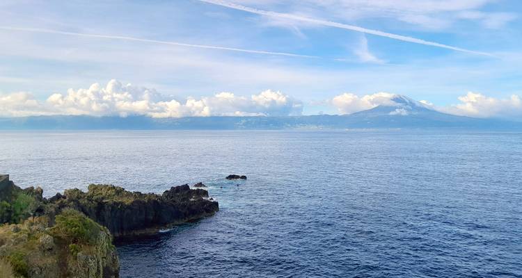 Expansive ocean view with distant island peaks under a sky streaked by high clouds.