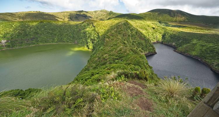 Deux lacs de cratère volcanique jumeaux - l'un vert, l'autre foncé - séparés par une crête étroite et végétalisée.