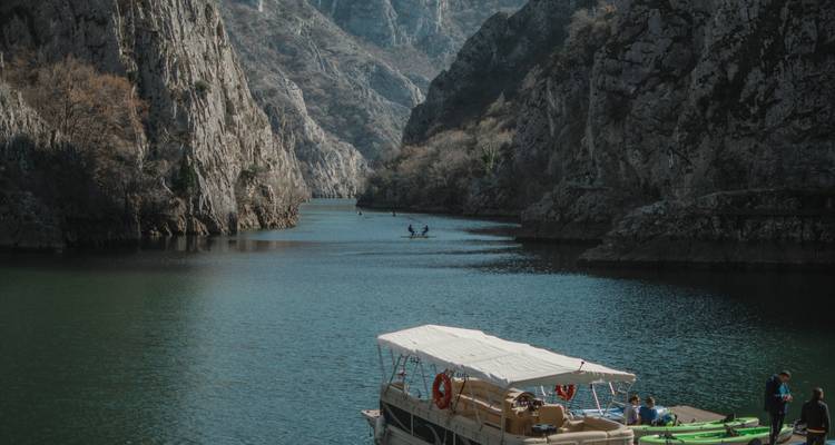 Paseos en bote por las aguas verde esmeralda y los acantilados escarpados del Cañón de Matka en un día tranquilo.