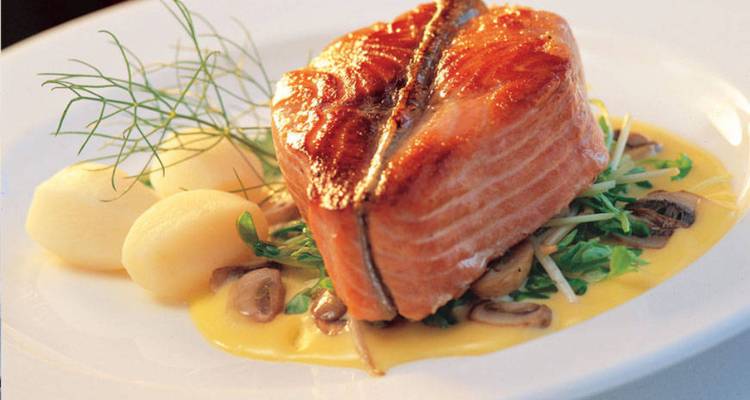 Gourmet salmon fillet served on creamy sauce with potatoes, mushrooms and fresh dill.