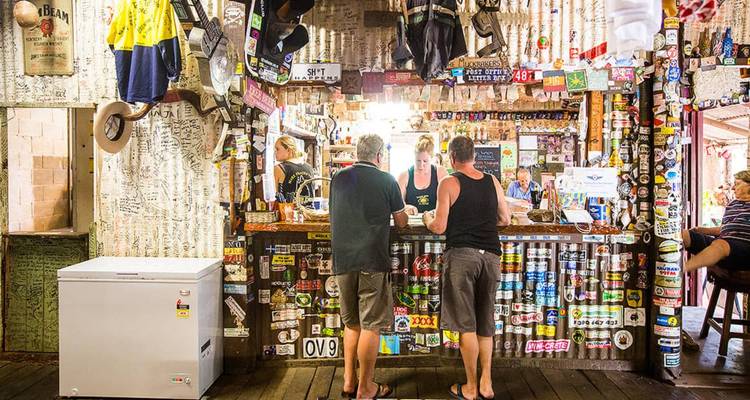 Intérieur rustique d'un pub de l'arrière-pays avec des clients discutant au comptoir recouvert de souvenirs.