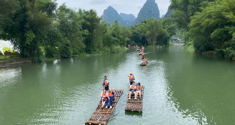 Des touristes sur des radeaux de bambou sur une rivière avec des montagnes karstiques en arrière-plan.