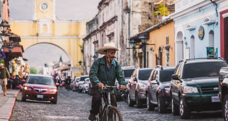 Hombre andando en bicicleta por una calle con edificios coloniales coloridos.