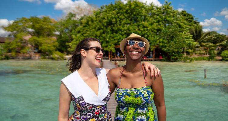 Dos mujeres sonriendo cerca de agua azul cristalina