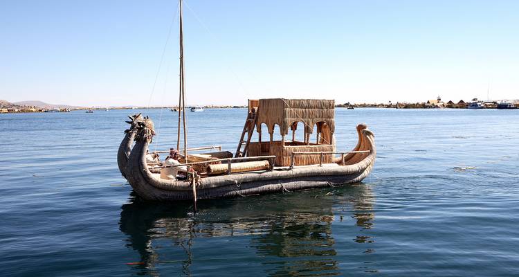 Traditional reed boat with a dragon prow floats on the deep blue waters of Lake Titicaca.