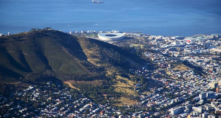 Luchtfoto van een stad met een stadion, berg en kustlijn.