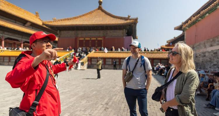 Guide touristique expliquant un site historique aux visiteurs avec une structure de toit traditionnelle.
