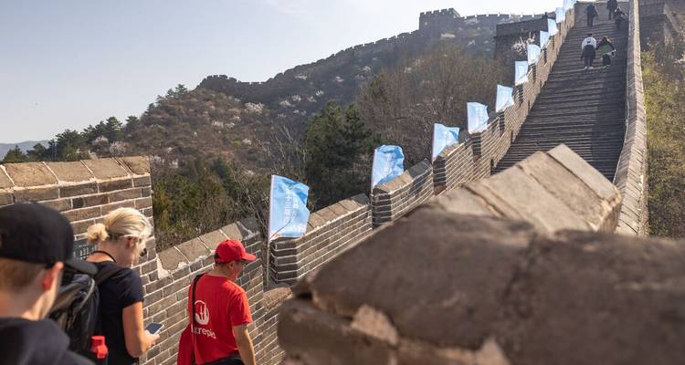 Des touristes marchant le long de la Grande Muraille de Chine avec des montagnes en arrière-plan.