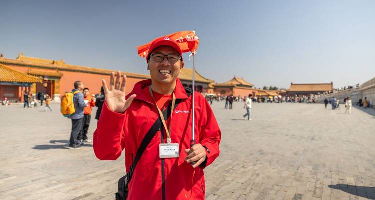 Smiling tour leader waves while holding a bright red flag in the expansive courtyard of the Forbidden City.