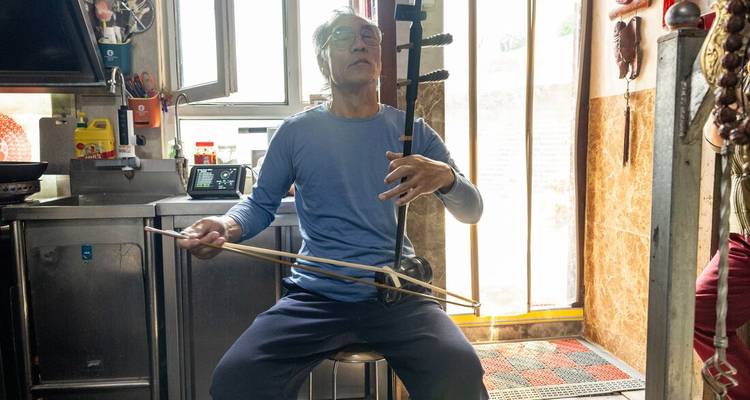 A man playing a traditional string instrument in an indoor setting.