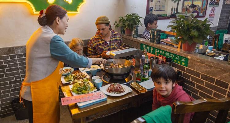 A family dining at a restaurant with a traditional Chinese meal.