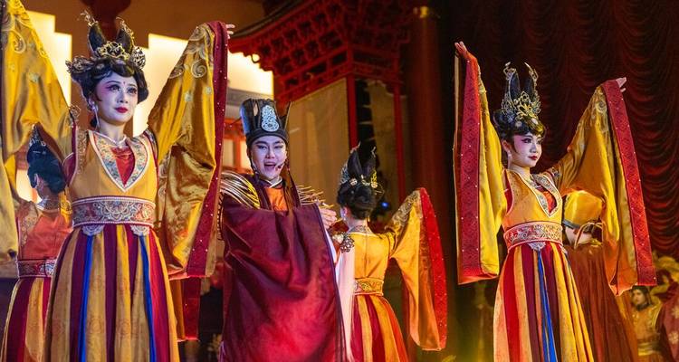 Un grupo de artistas con trajes tradicionales chinos en el escenario.