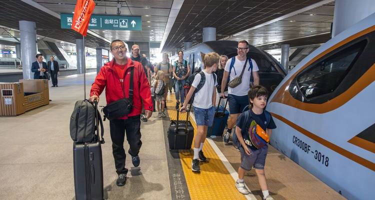 Personas caminando con equipaje cerca de una estación de tren.