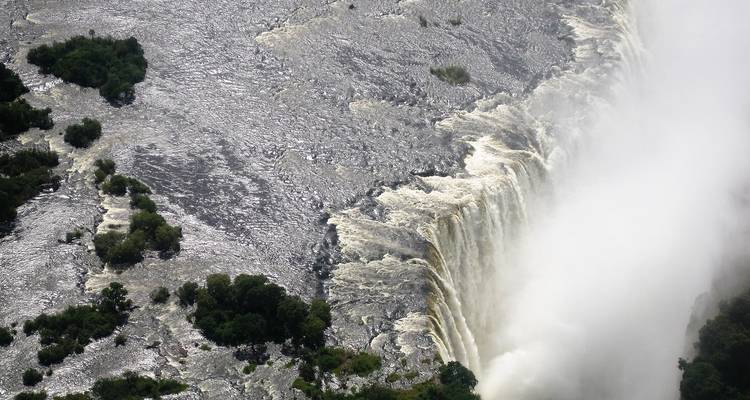 Bovenaanzicht van een waterval met water dat in een rivier stroomt.