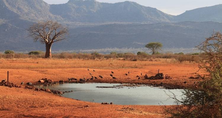 Small water body in a barren landscape with distant mountains.