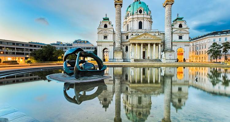 De Sint-Caroluskerk en haar spiegeling schitteren in een rustige poel tijdens het blauwe uur in Wenen.
