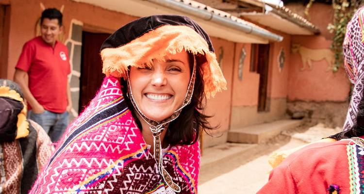 Woman in traditional attire smiling with others in the background.