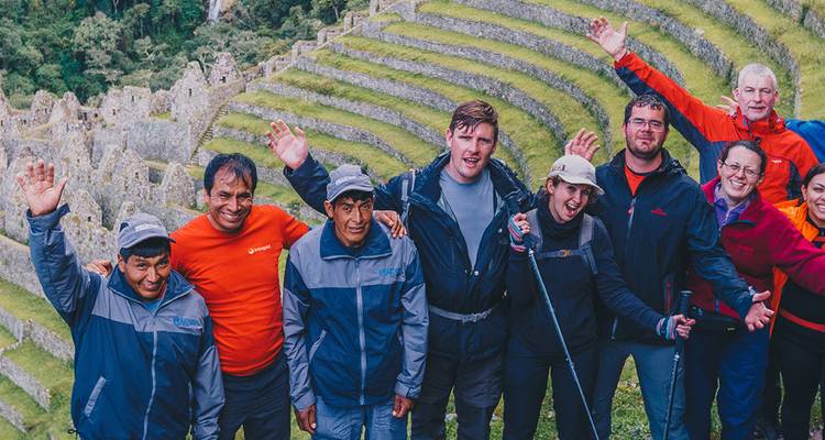 Gruppe von Menschen, die auf einer Terrasse der Inka-Ruinen winken.