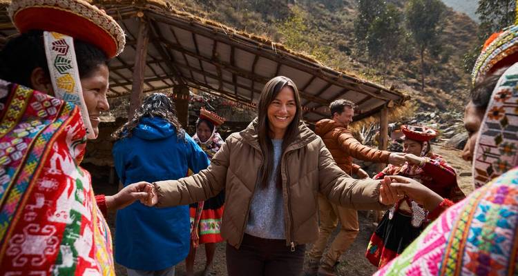A person dancing with locals in colorful traditional clothing.